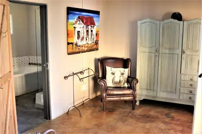 a room with a chair and a painting of a house at Round Here Self-Catering Holiday Home in Sabie