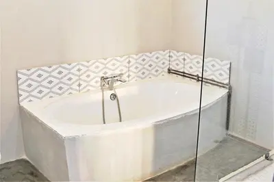 a bath tub in a bathroom with a glass wall at Round Here Self-Catering Holiday Home in Sabie