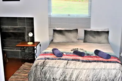 a bedroom with a bed with purple pillows on it at Round Here Self-Catering Holiday Home in Sabie