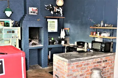 a kitchen with blue walls and a brick fireplace at Round Here Self-Catering Holiday Home in Sabie