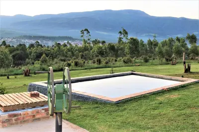 a swimming pool in a field with mountains in the background at Round Here Self-Catering Holiday Home in Sabie