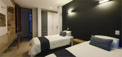 a bedroom with two beds and a black wall at Highland Gate House 1023 in Dullstroom