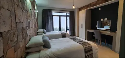 a hotel room with two beds and a desk at Highland Gate House 1023 in Dullstroom
