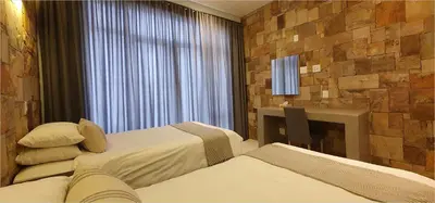 a hotel room with two beds and a desk and a window at Highland Gate House 1023 in Dullstroom