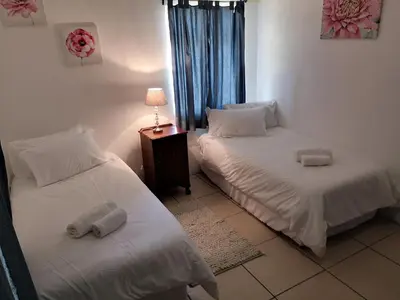 a room with two beds and a table with a lamp at Windsor Cottage in Barberton