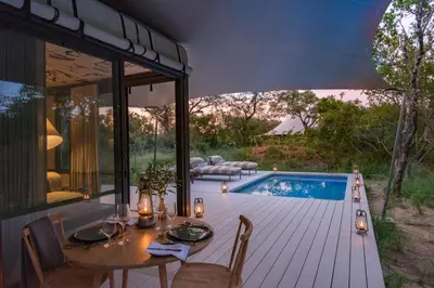 a dining area with a table and chairs next to a pool at Saseka Tented Camp in Hoedspruit