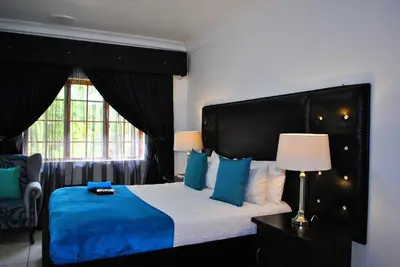 a bedroom with a bed with blue pillows and a window at Lapologa Bed & Breakfast in Tzaneen