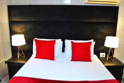 a bed with two red pillows and two lamps at Lapologa Bed & Breakfast in Tzaneen