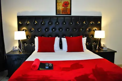 a bedroom with a bed with red pillows and two lamps at Lapologa Bed & Breakfast in Tzaneen