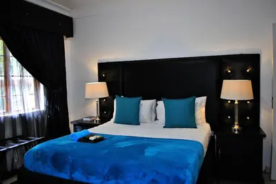 a bedroom with a large bed with blue sheets and pillows at Lapologa Bed & Breakfast in Tzaneen
