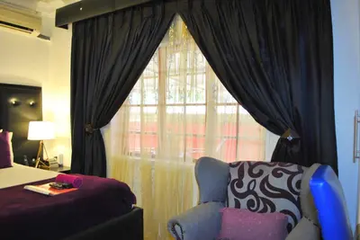 a bedroom with a bed and a chair and a window at Lapologa Bed & Breakfast in Tzaneen