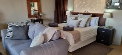a bedroom with a large bed and a couch at Watershed Guest House in Hartbeespoort