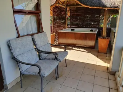 a pair of chairs and a tub in a room at Watershed Guest House in Hartbeespoort