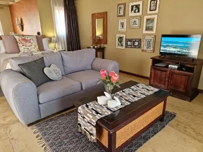 a living room with a couch and a tv at Watershed Guest House in Hartbeespoort