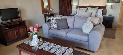 a living room with a couch and a tv at Watershed Guest House in Hartbeespoort