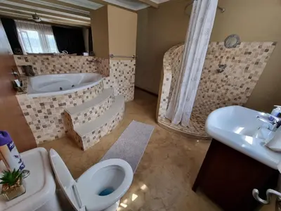 a bathroom with a tub and a toilet and a sink at Watershed Guest House in Hartbeespoort