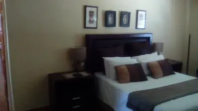 a bedroom with a bed and a table with a lamp at Phokela Guest House in Mokopane