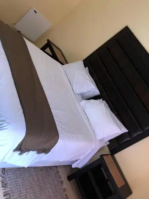a bedroom with a large bed with white sheets and pillows at Phokela Guest House in Mokopane