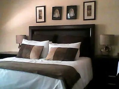 a bedroom with a large bed with three pictures on the wall at Phokela Guest House in Mokopane