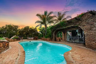 a swimming pool in front of a brick building at The Farm in Hartbeespoort