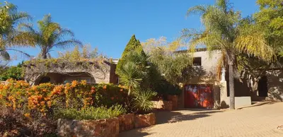 a house with trees and flowers in front of it at The Farm in Hartbeespoort