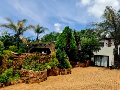 a house with a stone wall and plants at The Farm in Hartbeespoort