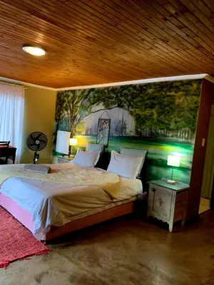 a bedroom with a bed with a painting on the wall at The Farm in Hartbeespoort