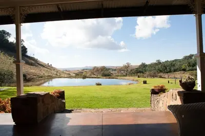 a view of a lake from the porch of a house at Connemara Trout Lodge in Dullstroom
