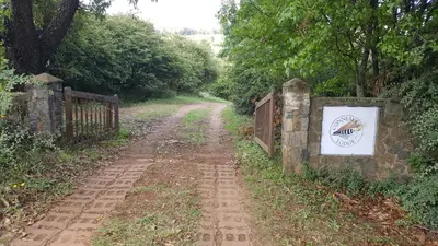 a dirt road with a sign on a fence at Connemara Trout Lodge in Dullstroom