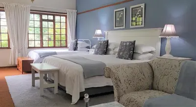 a bedroom with two beds and a couch at Brooks Cottage in Pretoria
