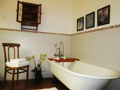 a bathroom with a white tub and a chair at Brooks Cottage in Pretoria