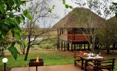 a tree house with a table and benches in front of it at Elephant Walk Retreat in Komatipoort