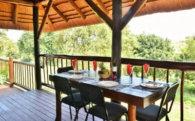 a wooden deck with a table and chairs on it at Elephant Walk Retreat in Komatipoort