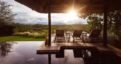 a patio with chairs and a table next to a pool at Khaya Ndlovu Safari Manor in Hoedspruit