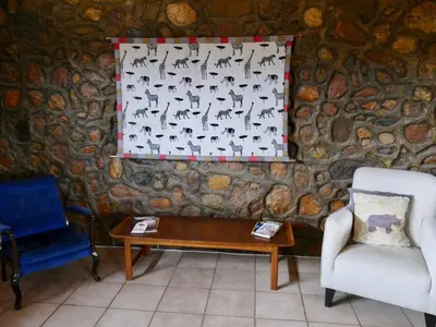 a room with a stone wall with a table and a chair at Adonsonia Lodge in Grietjie Nature Reserve