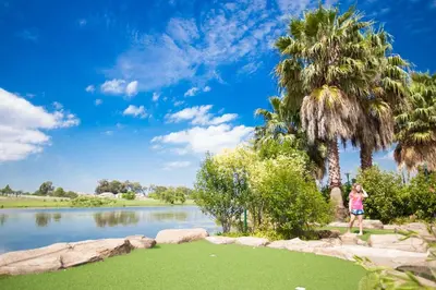a woman standing next to a lake with palm trees at Umuzi Lodge in Secunda