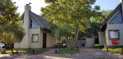 a small white building with trees in front of it at Umuzi Lodge in Secunda