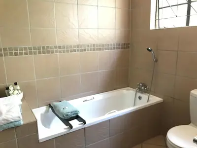 a bathroom with a bath tub with a towel on it at Contemporary Stay at Giraffe Cottage in Benoni
