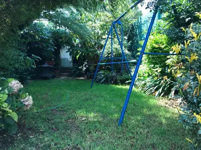 a blue swing set in the grass in a yard at Contemporary Stay at Giraffe Cottage in Benoni
