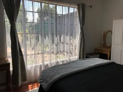 a bedroom with a bed and a large window at Contemporary Stay at Giraffe Cottage in Benoni