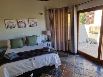 a bedroom with a bed and a sliding glass door at Gecko Lodge and Cottage, Mabalingwe in Warmbaths