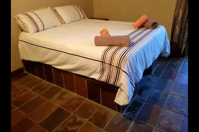 a bed with two towels on top of it at Gecko Lodge and Cottage, Mabalingwe in Warmbaths