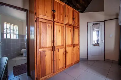 a bathroom with wooden cabinets and a toilet at 515 on Warthog by the River in Marloth Park