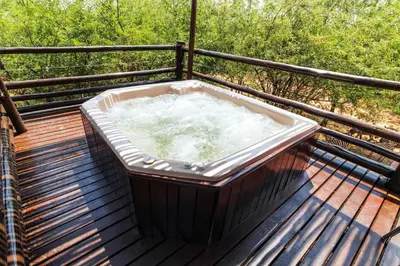 a hot tub on a wooden deck with trees at 515 on Warthog by the River in Marloth Park
