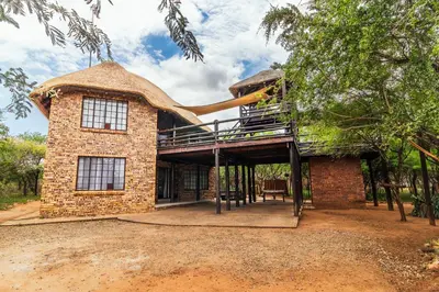 a house with a thatched roof and a deck at 515 on Warthog by the River in Marloth Park