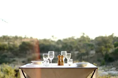 a table with wine glasses and plates on it at Ivory Wilderness River Rock Lodge in Klaserie Private Nature Reserve