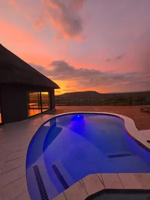 a blue swimming pool with a sunset in the background at Bona Kgole Private Game Lodge, Mabalingwe in Warmbaths
