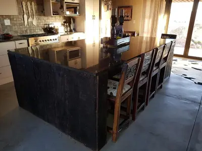 a kitchen with a large wooden counter with chairs at Lodge Twentyfour Mabalingwe Nature Reserve in Warmbaths
