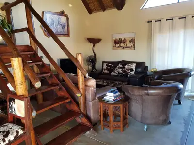 a living room with a staircase and a couch at Lodge Twentyfour Mabalingwe Nature Reserve in Warmbaths