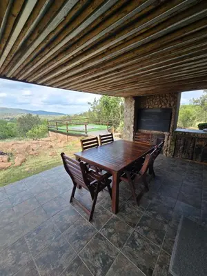a wooden table and chairs on a patio at Lodge Twentyfour Mabalingwe Nature Reserve in Warmbaths